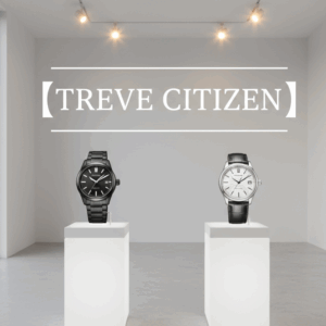 「【TREVE CITIZEN】」のホワイトロゴが壁面に大きく配された、ミニマルで清潔感あふれる鑑定展示スペース。2つの白い展示台の上には、左側に精悍なオールブラックのチタンモデル、右側に洗練されたシルバー文字盤にレザーストラップを組み合わせたシチズンの高級腕時計が、美術館のように美しくディスプレイされている。高松市の時計買取専門店「TREVE」が、エコ・ドライブの動作精度や外装のコンディションを精密に鑑定するイメージ。