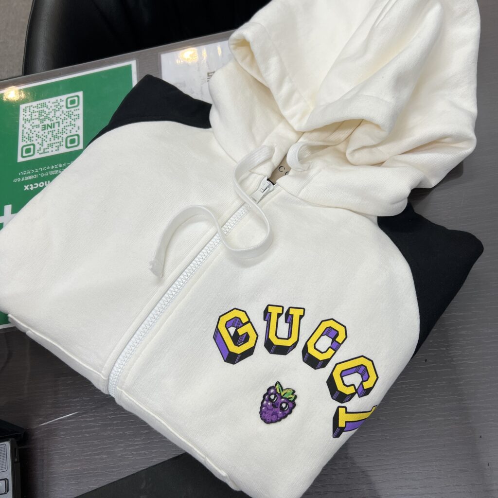高松市で買取したグッチの未使用ジップアップパーカー 773729。白と黒のバイカラーデザイン。