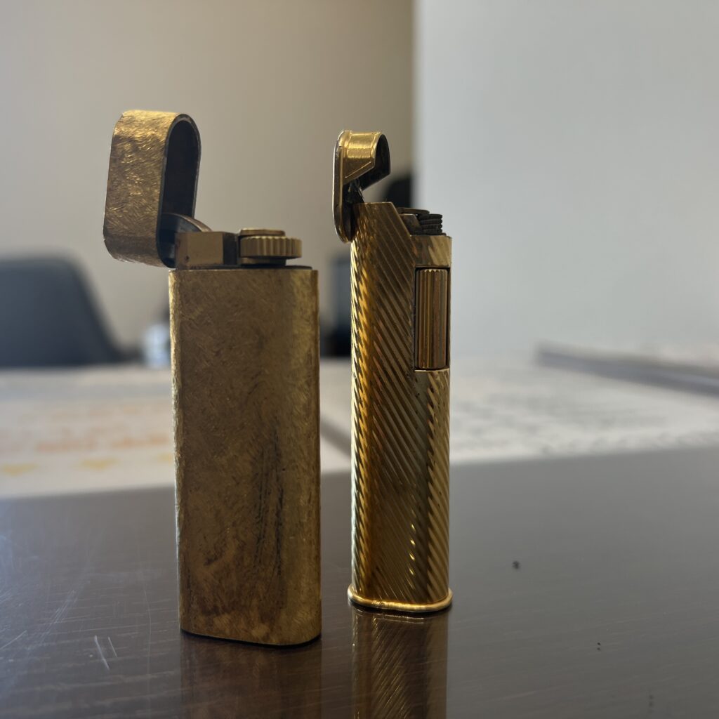 高松市のトレリバで買取したカルティエとダンヒルのゴールドガスライター。蓋が開けられた状態で並ぶ接写。