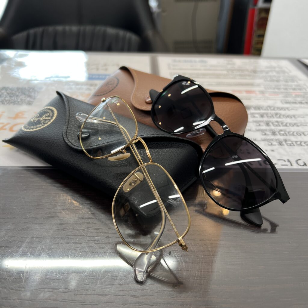 高松市のトレリバで買取したレイバンのサングラスとメガネ。黒と茶色の純正レザーケースの上に置かれたアイウェア2点の画像。