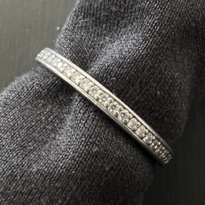 観音寺のお客様から高松市のトレリバで買取したPt950ダイヤモンドハーフエタニティリング。グレーの布の上に置かれた豪華なプラチナ宝飾ジュエリーの画像。
