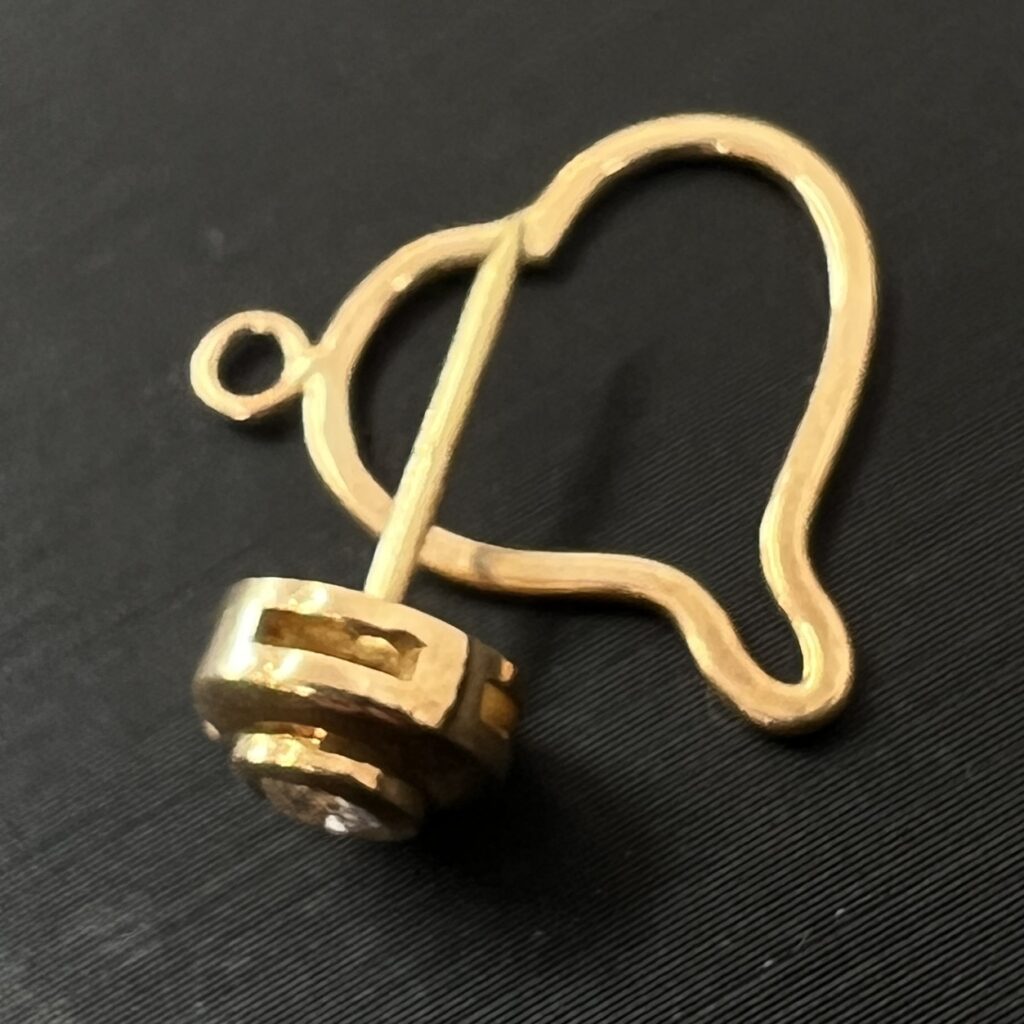 高松市のトレリバで買取したK18イエローゴールドのペンダントトップ。テーブルの上に置かれた、多面カットが施された18金製品の画像。