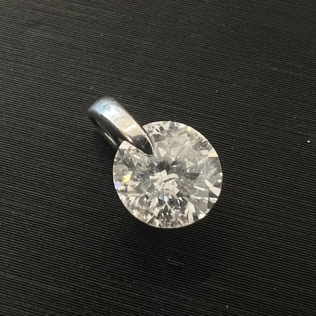高松市のトレリバで買取した1ctオーバーのPt900天然ダイヤモンドペンダントトップ。黒い背景の上に置かれた大粒の一粒ダイヤ宝飾ジュエリーの画像。