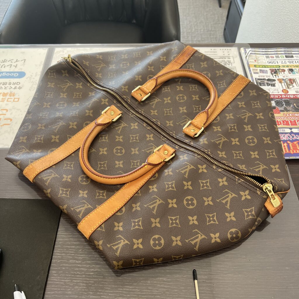 高松市のトレリバで買取したルイ・ヴィトン（LOUIS VUITTON）のモノグラムボストンバッグ「キーポル50」。テーブルの上に置かれたバッグ本体とアメ色に変化したハンドルの画像。