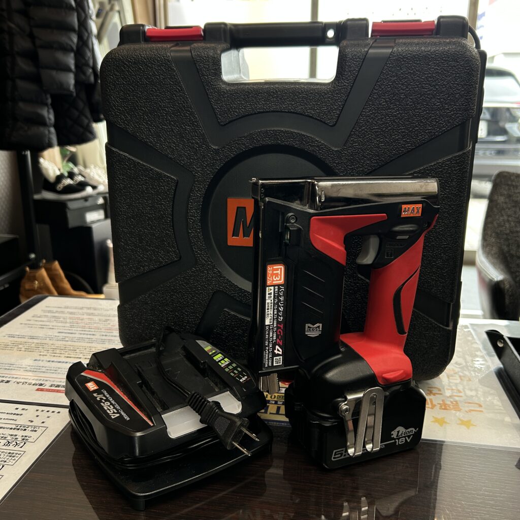 高松市のトレリバで買取したMAX（マックス）の充電式タッカTG-Z4。黒いプラスチックケースの前に置かれた赤と黒のプロ用中古電動工具の画像。