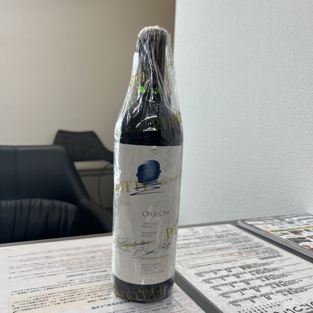 高松市のトレリバで買取した高級カリフォルニアワイン「オーパスワン2010」。黒い布の上に立てられた、未開封でラベルが綺麗なヴィンテージボトルの画像。
