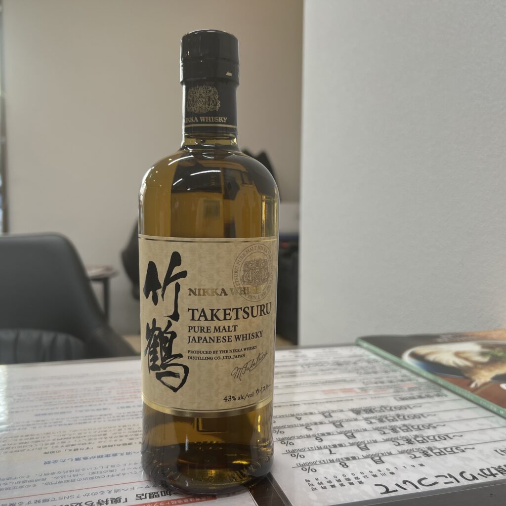 高松市のトレリバで買取したニッカ竹鶴ピュアモルトウイスキー。テーブルの上に置かれた未開封のウイスキーボトルの画像。