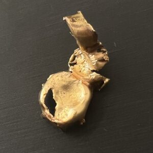 高松市のトレリバで買取した金歯。黒い背景の上に置かれた歯科用貴金属ゴールドクラウンの画像の写真。
