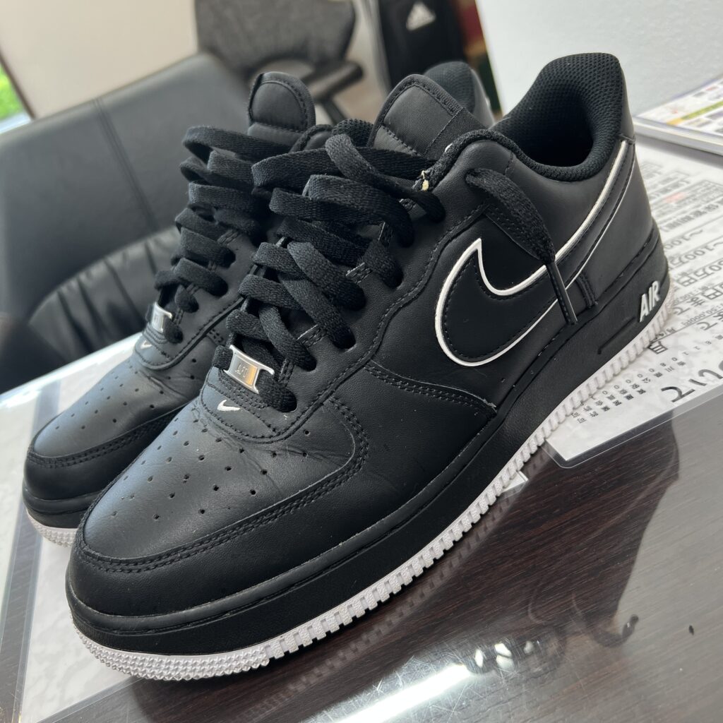 高松市のトレリバで買取したナイキ（NIKE）のエアフォース1スニーカー。テーブルの上に置かれた黒いレザーアッパーと白いソールの画像。