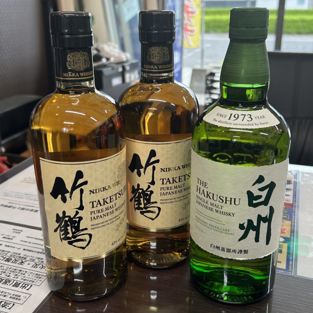 高松市のトレリバで買取した竹鶴と白州のウイスキー。テーブルの上に置かれた、未開封の3本の国産ウイスキーボトルの画像。
