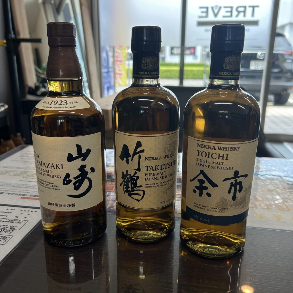 高松市のトレリバで買取した山崎、竹鶴、余市のウイスキー。テーブルの上に置かれた、未開封の3本のプレミアム国産ウイスキーボトルの画像。
