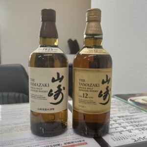 高松市のトレリバで買取したサントリーウイスキー山崎12年とNV。テーブルの上に並べられた未開封のシングルモルトウイスキーボトルの画像。
