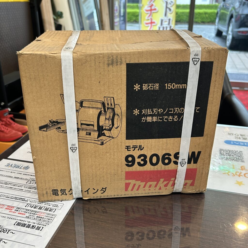 高松市のトレリバで買取したマキタ（makita）の電気グラインダ（9306SW）。テーブルの上に置かれた、白い梱包バンドが掛けられた茶色い段ボール外箱パッケージの画像。