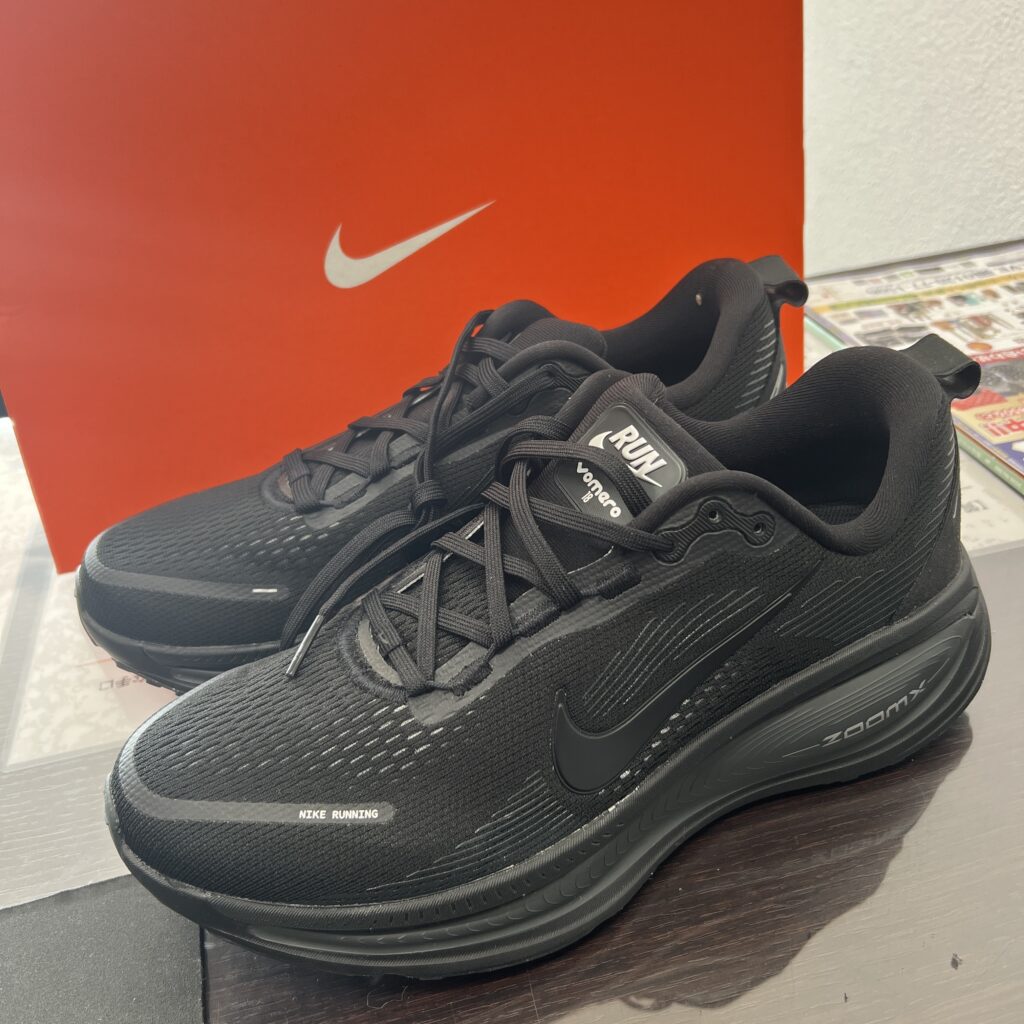 高松市のトレリバで買取したナイキ（NIKE）のランニングスニーカー「ズーム ボメロ 18」。テーブルの上に置かれた黒いスニーカー本体と、後ろにあるオレンジの純正箱の画像。