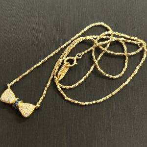 高松市のトレリバで買取したK18サファイアダイヤモンドネックレス。黒い背景の上に置かれた金のリボンモチーフネックレスの画像。