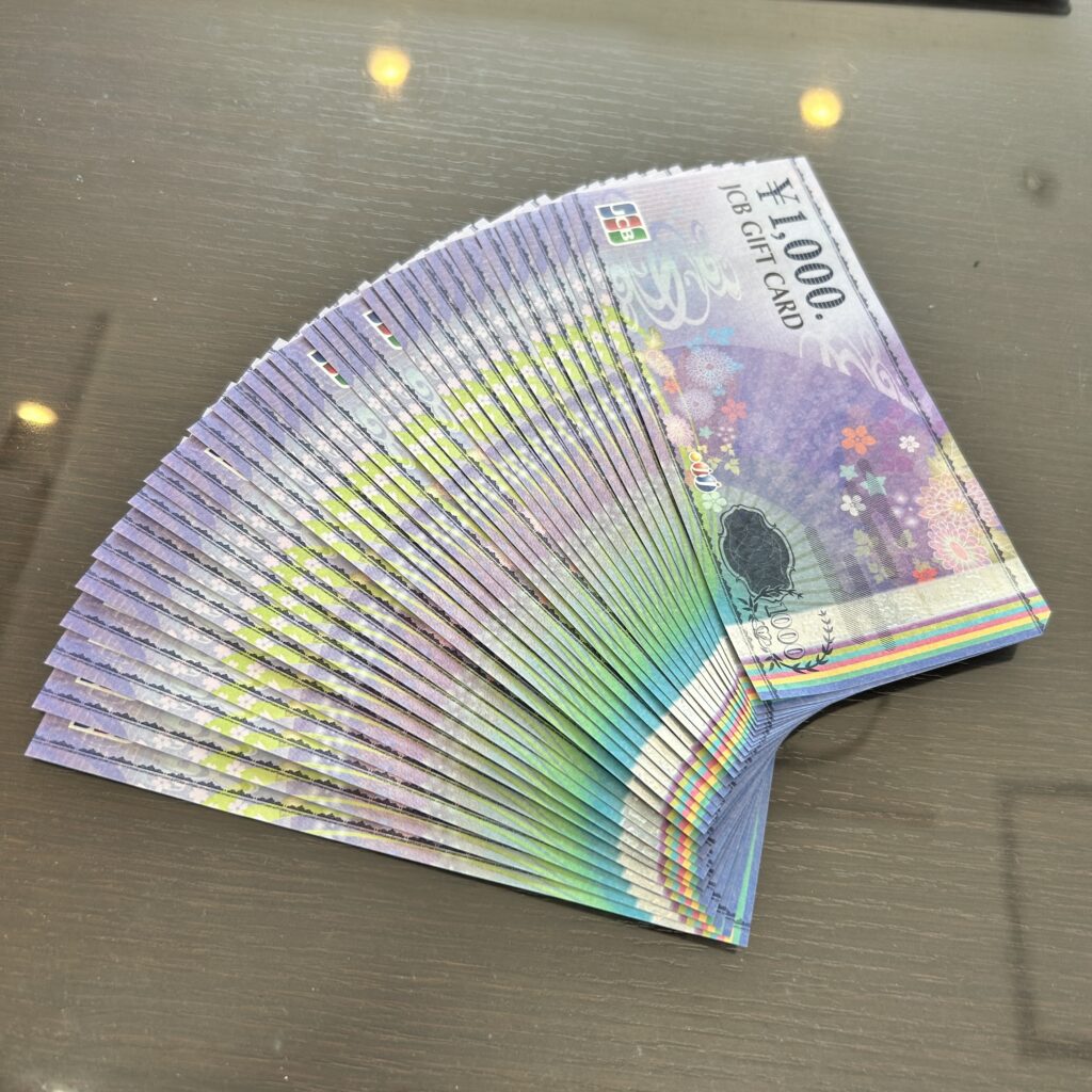 高松市のトレリバで買取したJCBギフトカード。テーブルの上にキレイな扇状に広げられた1,000円券の大量まとめの画像。