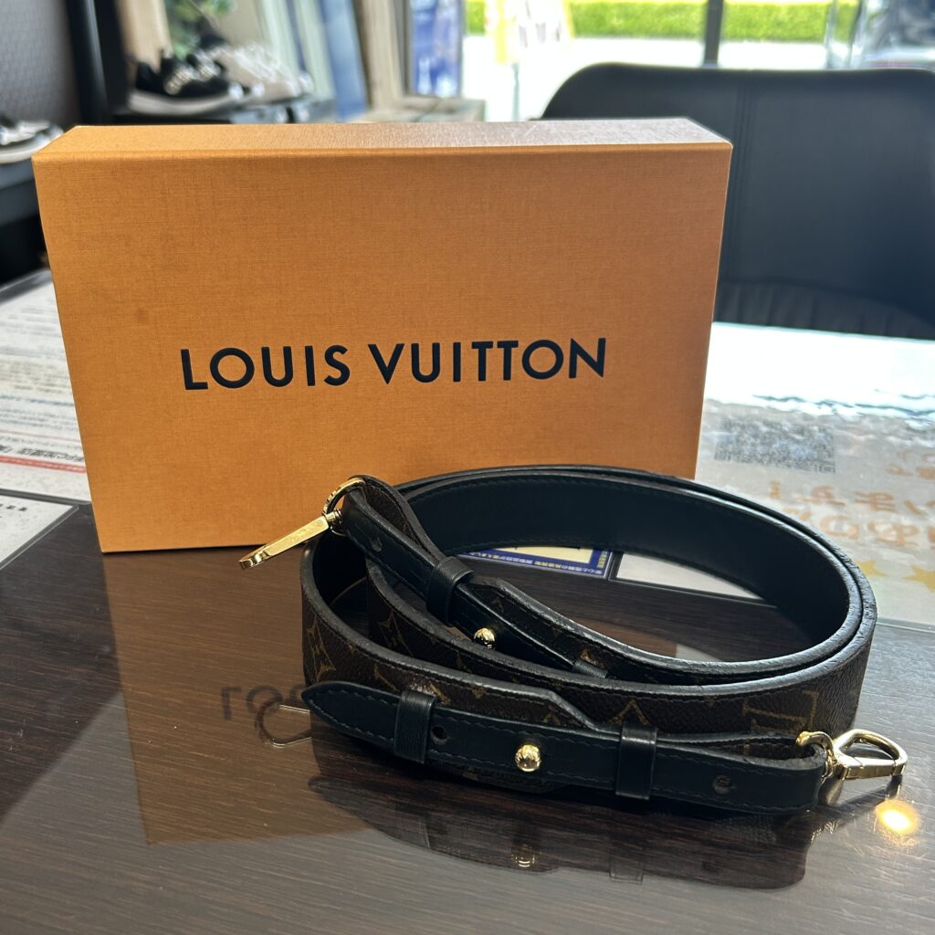高松市のトレリバで買取したルイ・ヴィトンのショルダーストラップ。オレンジのLV外箱の前に置かれたモノグラム柄ショルダーストラップの画像。