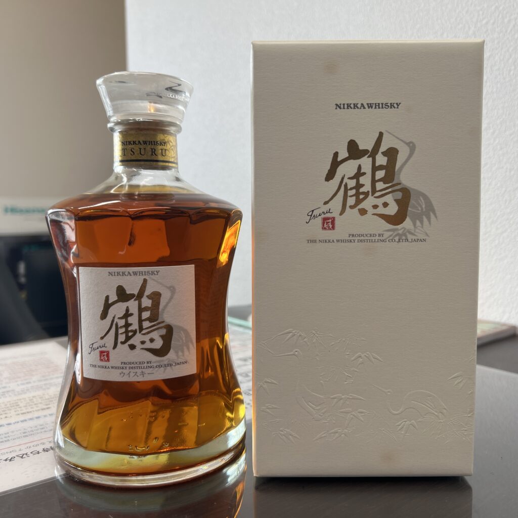 高松市のトレリバで買取したニッカウイスキー鶴。白い専用化粧箱の横に置かれたウイスキーボトルの画像。